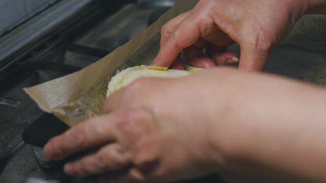 Female hands placing Chinese cabbage on baking sheet covered with baking paper.