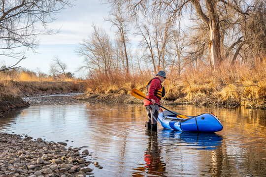 senior male paddler is launching his inflatable packraft on a river in early spring - Poudre River in northern Colorado