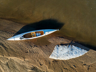 decked expedition canoe on a sandbar with ice floe - South Platte River in eastern Colorado