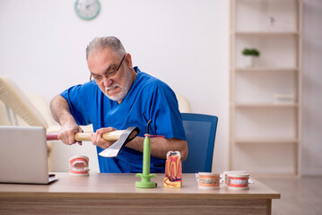 Old male dentist working in the clinic