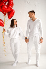 A girl with her beloved boyfriend with a bunch of red foil balloons in the shape of a heart. Valentine's Day is a holiday for lovers