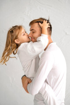 The daughter gently kisses Dad on the nose. A child in strong male hands. Father's Day