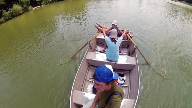 Boy, girl, man and woman in boat on pond, action camera