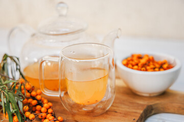 clear glass cup filled with aromatic sea buckthorn tea, alongside a transparent teapot