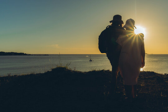 silhouette of a scorched woman and man watch the sunset over the sea from a hill. copy space