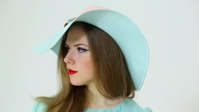 Face of cute young woman in big cyan hat closeup at studio