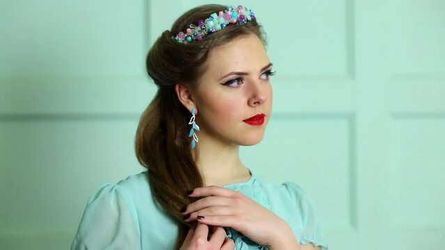 Cute young woman touches her hair while dreams in studio