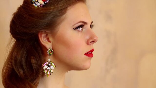 Profile of young woman with big earring near wall in studio