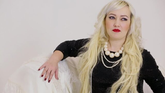Blonde poses with necklace and diadem on blond curly hairs
