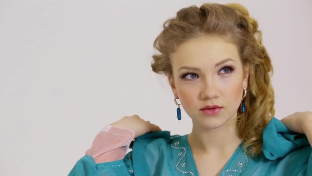 Young woman puts off and then returns hood of cyan dress