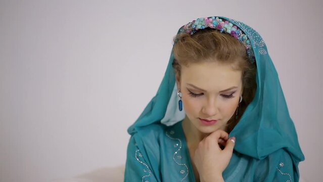 Young woman look around in cyan dress with hood and diadem on head