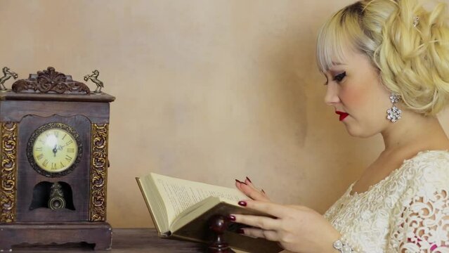Woman with blond hair reads book near retro clock with pendulum