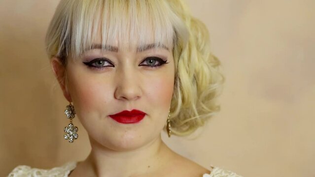 Face of blonde with make-up and earrings which poses in studio