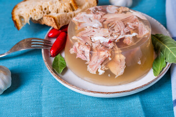 Jelly with meat, beef aspic, traditional dish. portion on plate. Bread and chili.