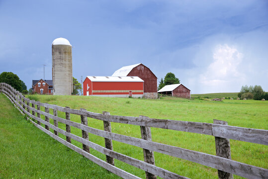 Agriculture landscape with red barn and silo with fence
