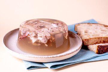 Jelly with meat, beef aspic. Portion on plate with bread.