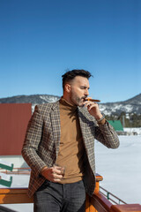 Handsome man drinking whisky and smoking ciggaret outdoor