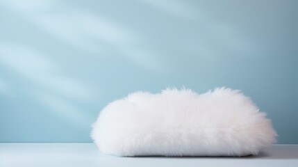  a fluffy white pillow sitting on top of a white table next to a light blue wall and a light blue wall behind it.