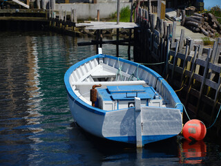 Fototapeta na wymiar A colorful blue and qhite motorboat docked at the harbor in themvillage of Quidi Vidi Newfoundland