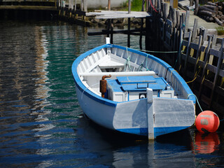 A colorful blue and qhite motorboat docked at the harbor in themvillage of Quidi Vidi Newfoundland