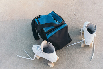 A lone blue backpack with quad roller skates in the asphalt.