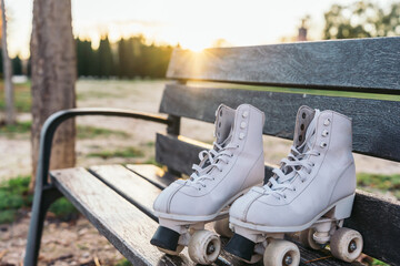 Abandoned Quad Roller Skates on a Wooden Bench. Pair of skates at sunset symbolizing the end of the training day.