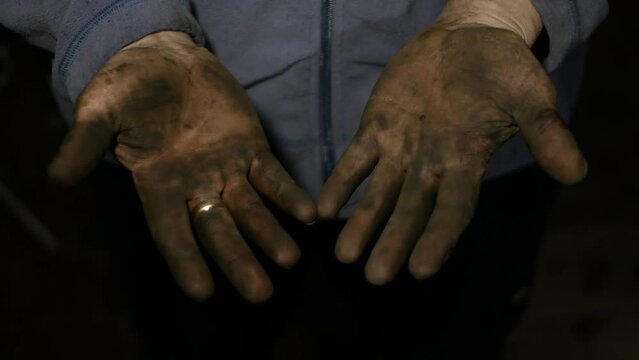 An auto mechanic shows off his very dirty hands covered in grease after work. Footage from an amateur car service.
