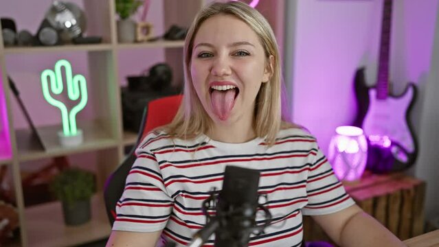 Blonde bombshell gamer gal, jubilantly sticking her tongue out, radiating crazy joy while streaming! young woman's hilarious facial expression lights up the fun night in a home gaming room.