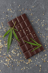 Whole organic dark chocolate bar with infused crushed hemp seeds on stone background