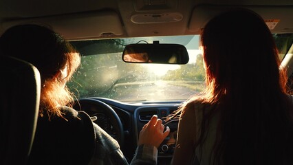 Two happy redhead young female friends dancing having fun driving car road trip closeup back view. Smiling woman relaxing dance music radio automobile journey adventure escape at bright sun light