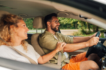 Happy family is driving a car during a weekend trip away from the city