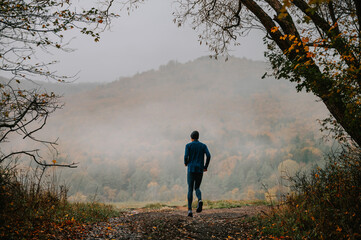 A Young Trail Runner's Harmonious Connection with Foggy Autumn