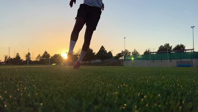 Video of a soccer player hitting the ball at sunset on a soccer field.