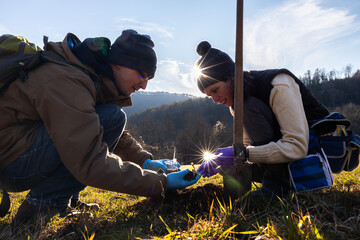 Young Adult Biologists Researching Soil Composition on a Farm Field in A Sunny Winter Day