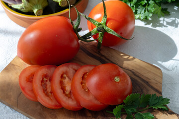 Ripe red Roma tomatoes in bowl with fresh herbs