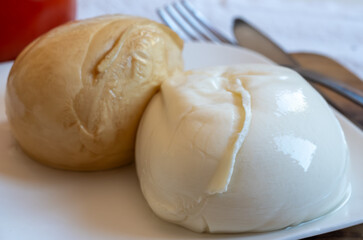 Tasty Italian food, small balls of white and smoked mozzarella soft cheese close up