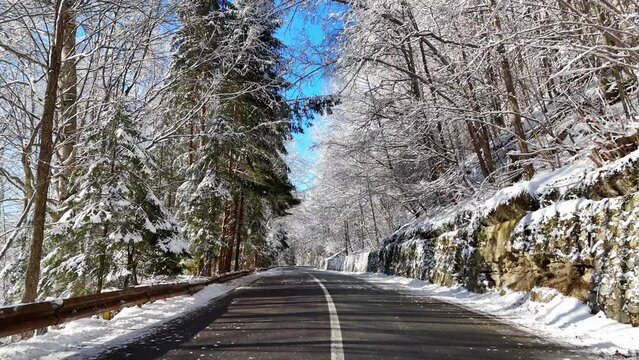 Empty asphalt winter mountain road. Beautiful winter landscape with mountain road among snow covered trees. Asphalt road in the mountain forest covered with snow. Frozen forest. Winter season. 