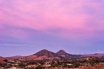 Pink sunset over mountain peaks, town, city
