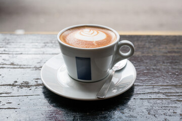 Flat White Coffee with latte art, on top of rustic wood table.