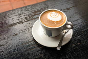 Flat White Coffee with latte art, on rustic wood table. High angle or top view.