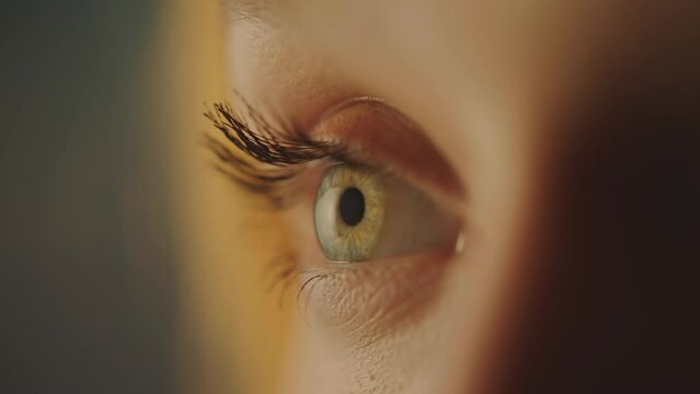 Side view of young woman with incredible light brown eyes. Close up shot of eye opening with beautiful teal iris
