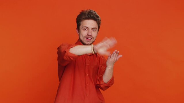 Caucasian man showing wasting throwing sharing money around, more tips, big profit, winning lottery jackpot, successful shopping payment purchase cashback. Handsome guy isolated on orange background