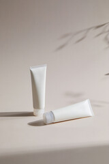 Warm natural light and beige background. White skincare products. the shadow of the floor.
