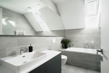 The image depicts a bright, modern bathroom with a white sink, mirror, toilet, and built-in...