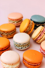 Beautiful multicolored macarons, many fillings, on a light pink background.