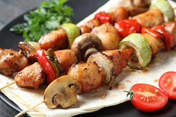 Delicious shish kebabs with vegetables on table, closeup