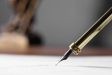 Writing on document with fountain pen at table, closeup and space for text. Notary contract