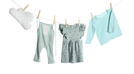 Different baby clothes and cloud shaped pillow drying on laundry line against white background