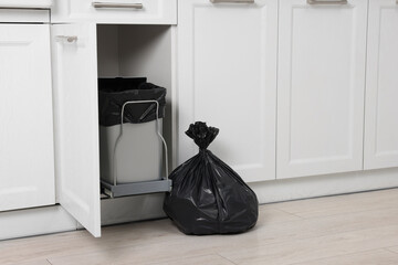Plastic garbage bag and trash can indoors. Space for text