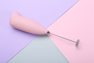 Pink milk frother wand on color background, top view